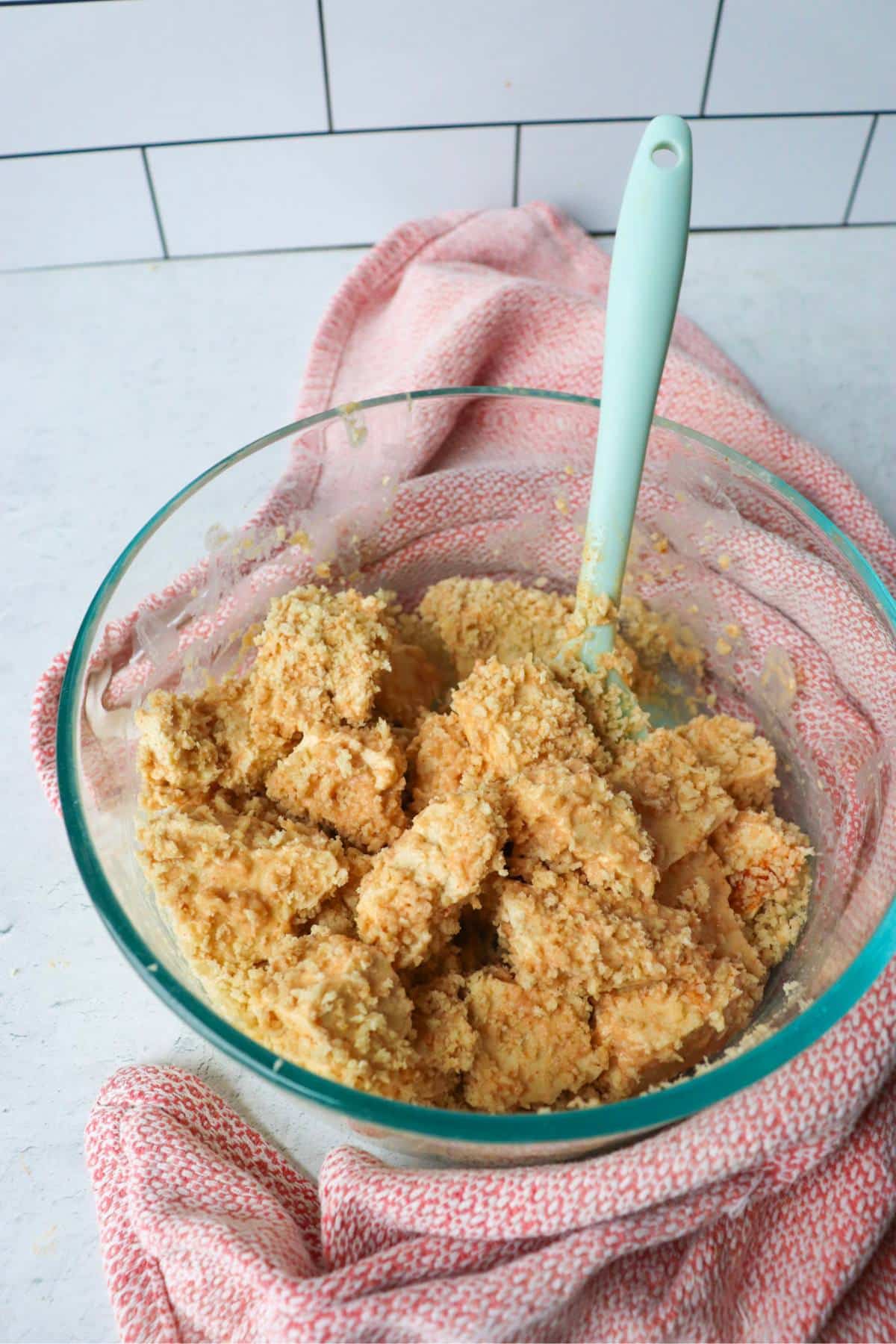 Tofu cubes in a bowl with bread crumbs.