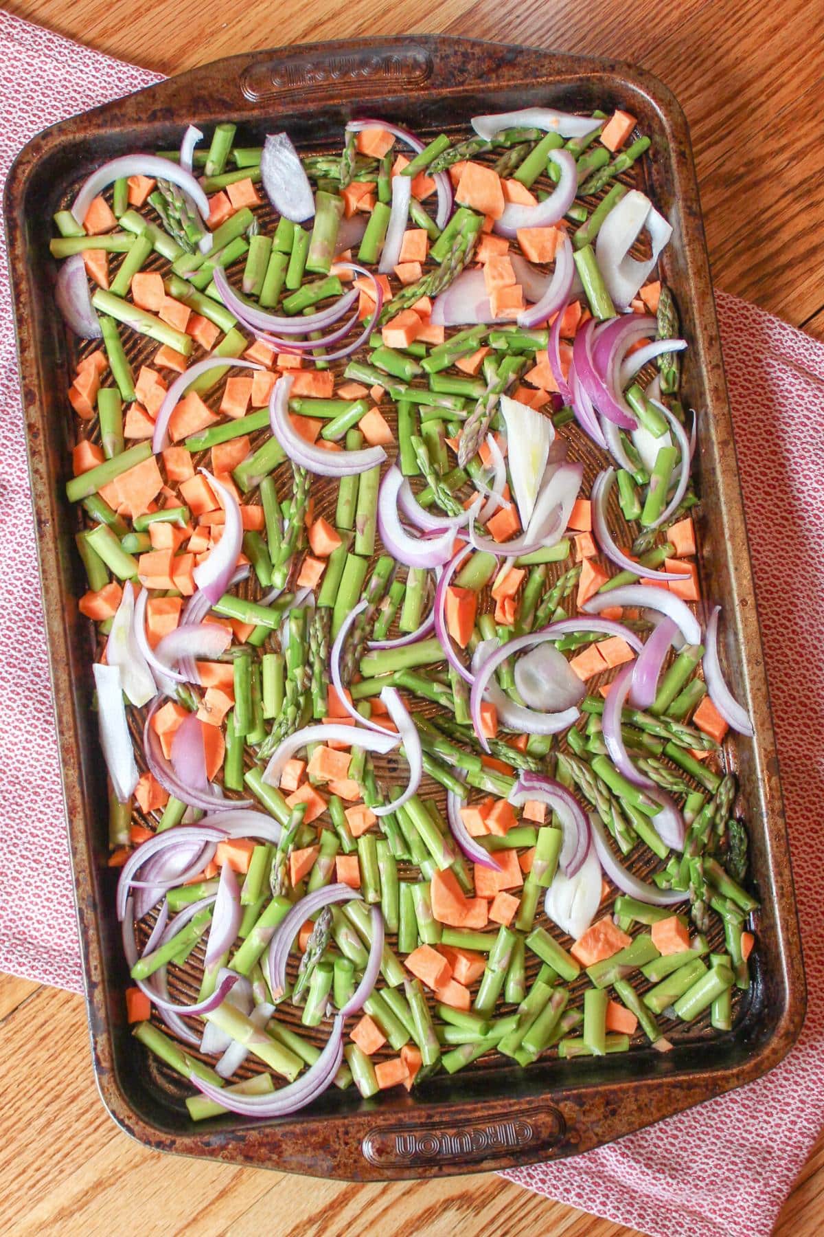 A baking sheet pan full of asparagus, sweet potatoes and red onions.