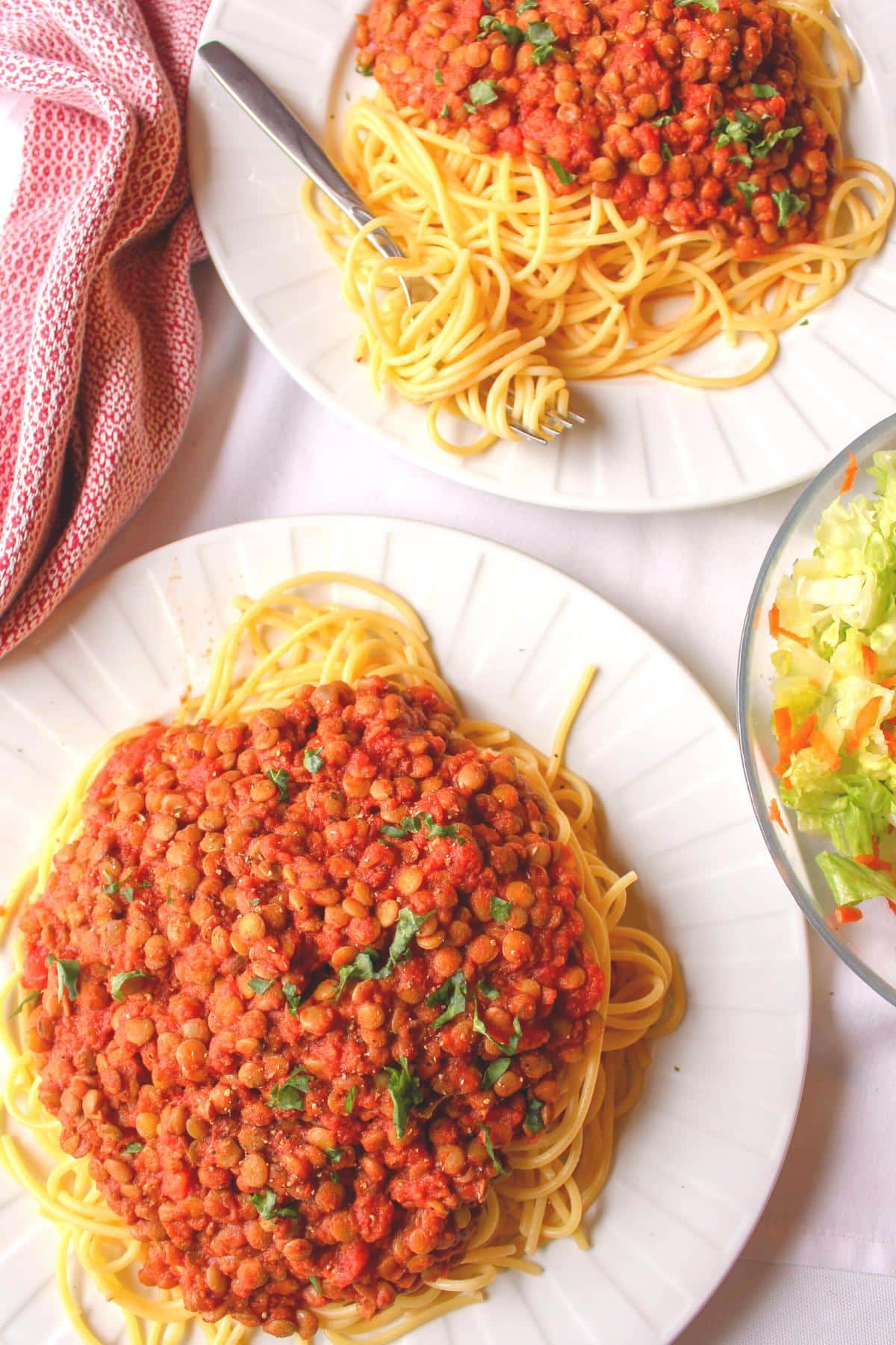 Overhead view of two plates filled with spaghetti and lentil pasta sauce.