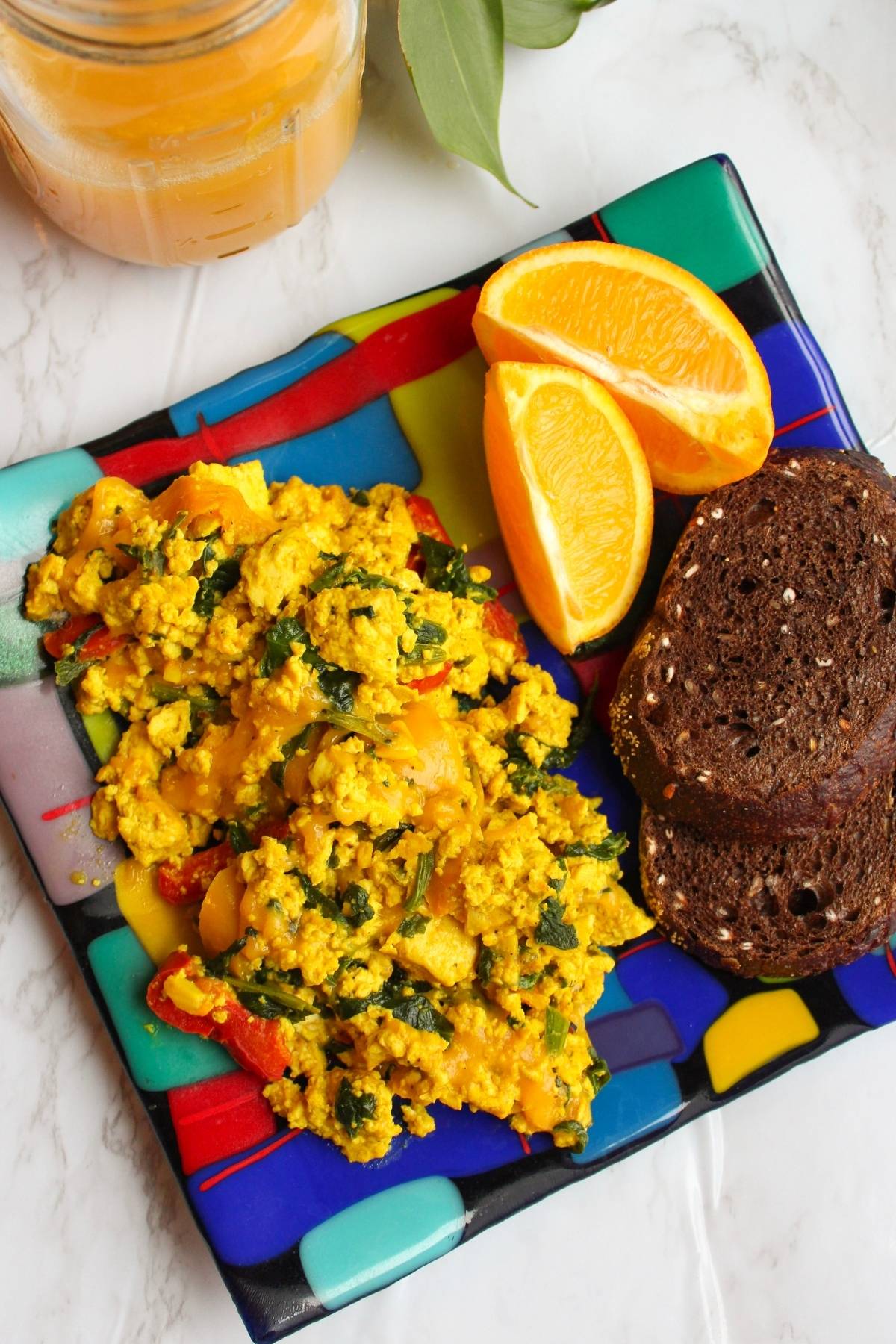 Plate with vegan scrambled eggs, toast and orange slices.