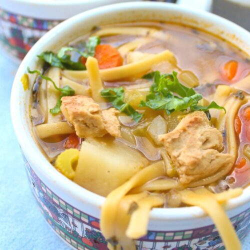 Close up of vegetarian chicken noodle soup in a large mug.