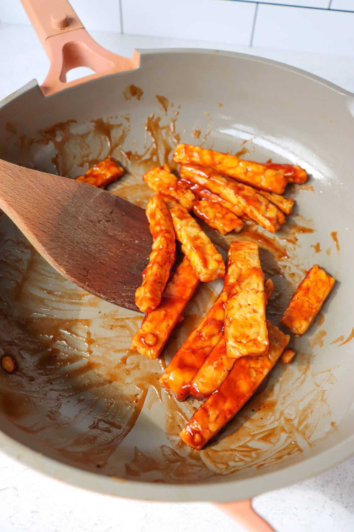 Tempeh strips in a pan with bbq sauce.