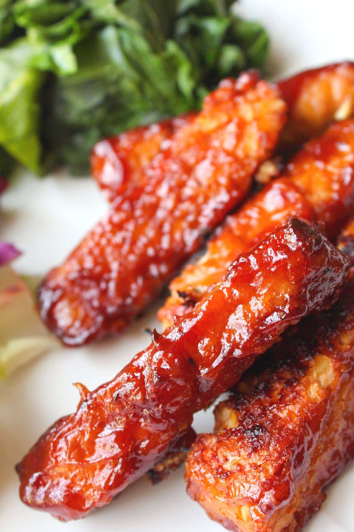 BBQ tempeh strips on a plate with collard greens
