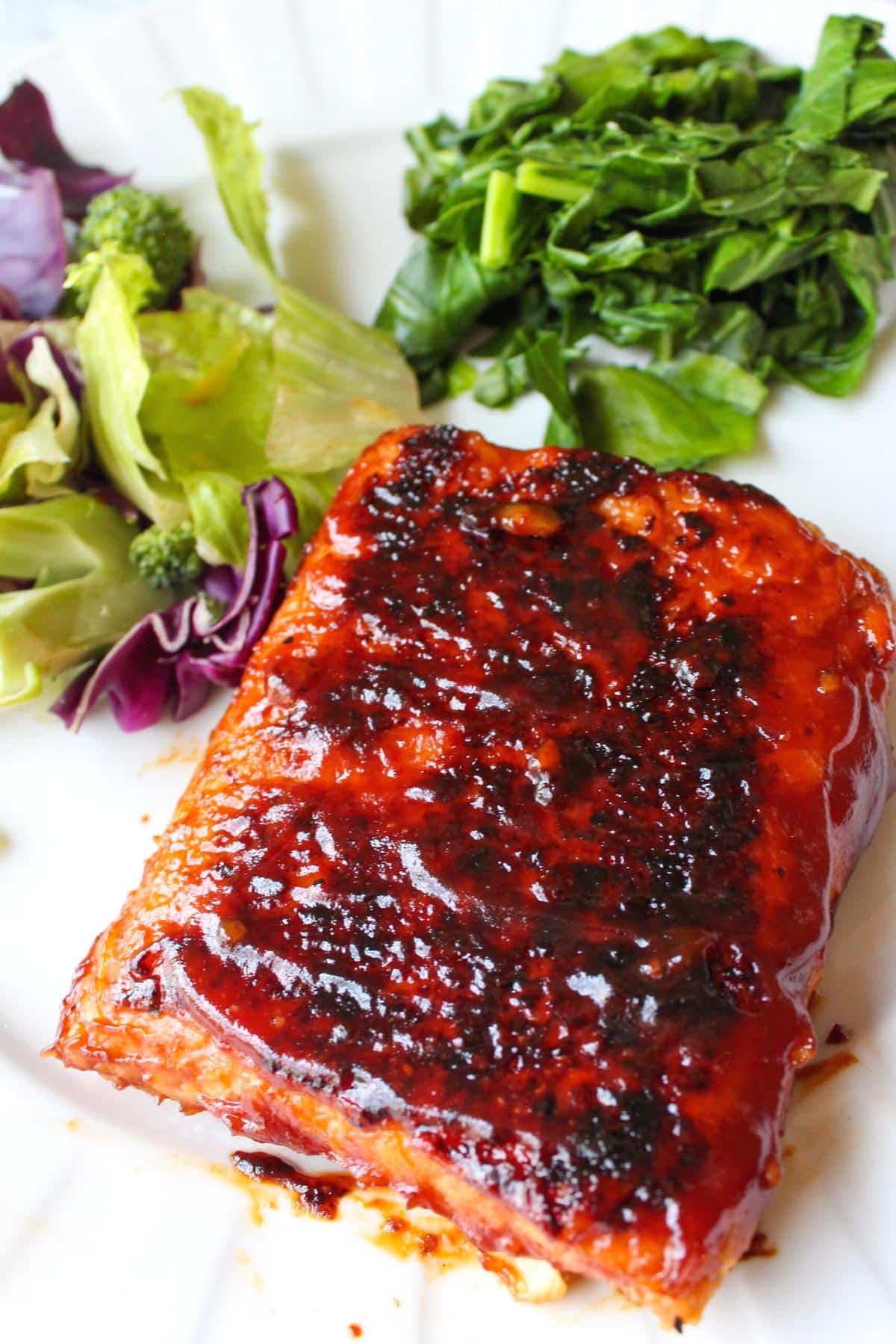 Block of bbq tempeh on a plate with salad. 