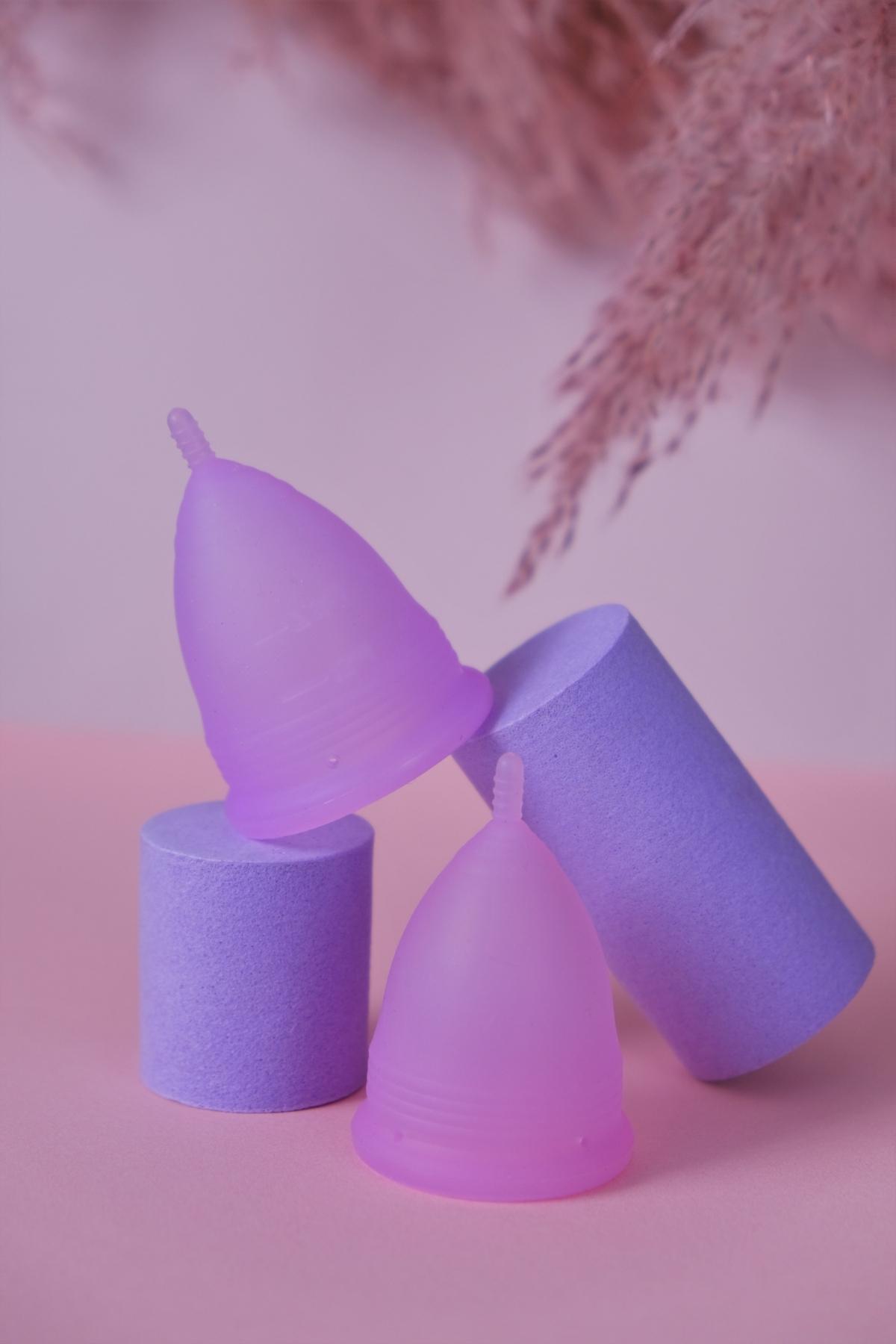 Two purple menstrual cups balancing on each other