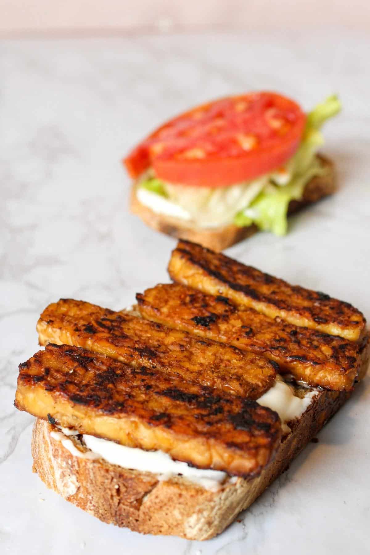 Smoky tempeh strips on a piece of bread