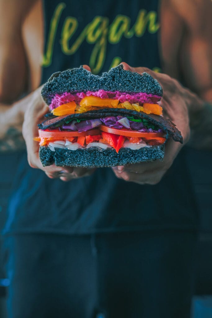 hand holding a colorful and large veggie sandwich
