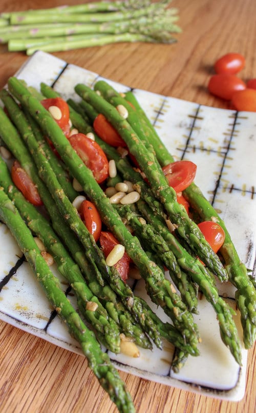 air fried asparagus on a plate with cherry tomatoes