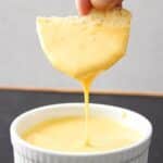 Hand dipping a chip into vegan nacho cheese
