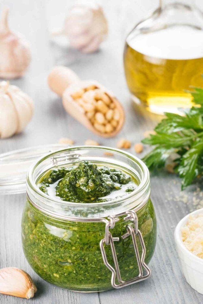 Jar of dairy free pesto with ingredients in the background