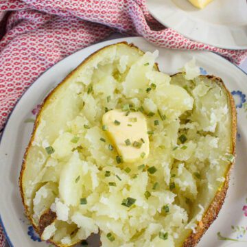 Air fryer baked potato cut in half with melted butter on top
