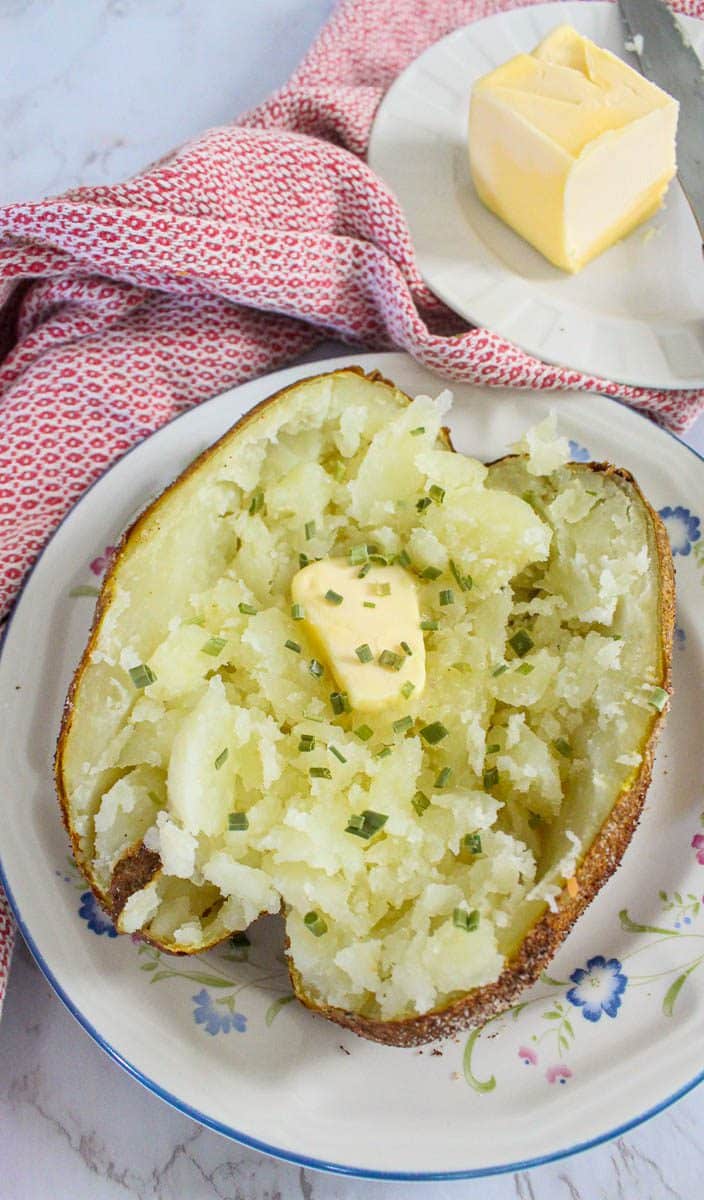 Air fryer baked potato cut in half with melted butter on top