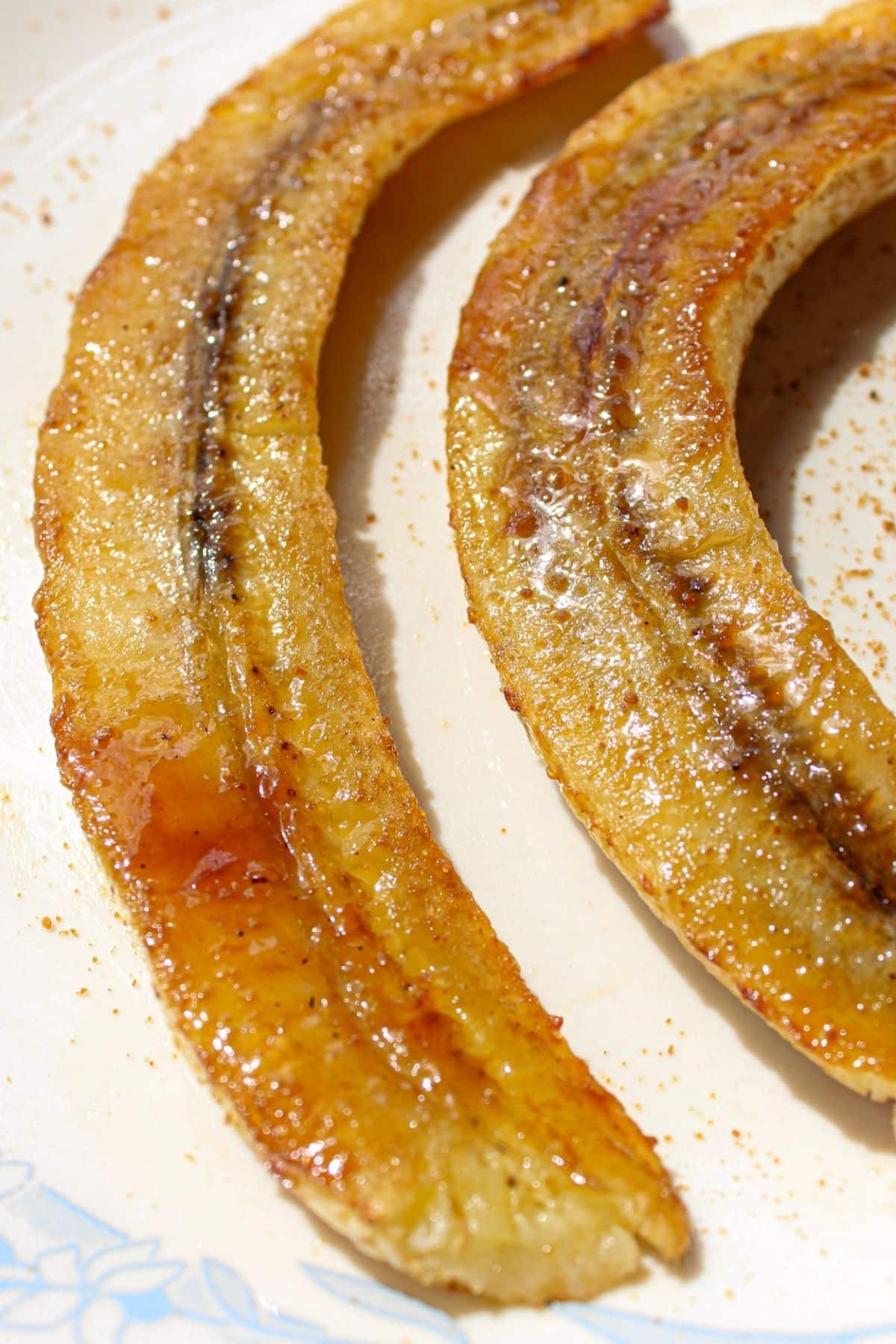 Caramelized air fryer bananas cut in half on a plate. 