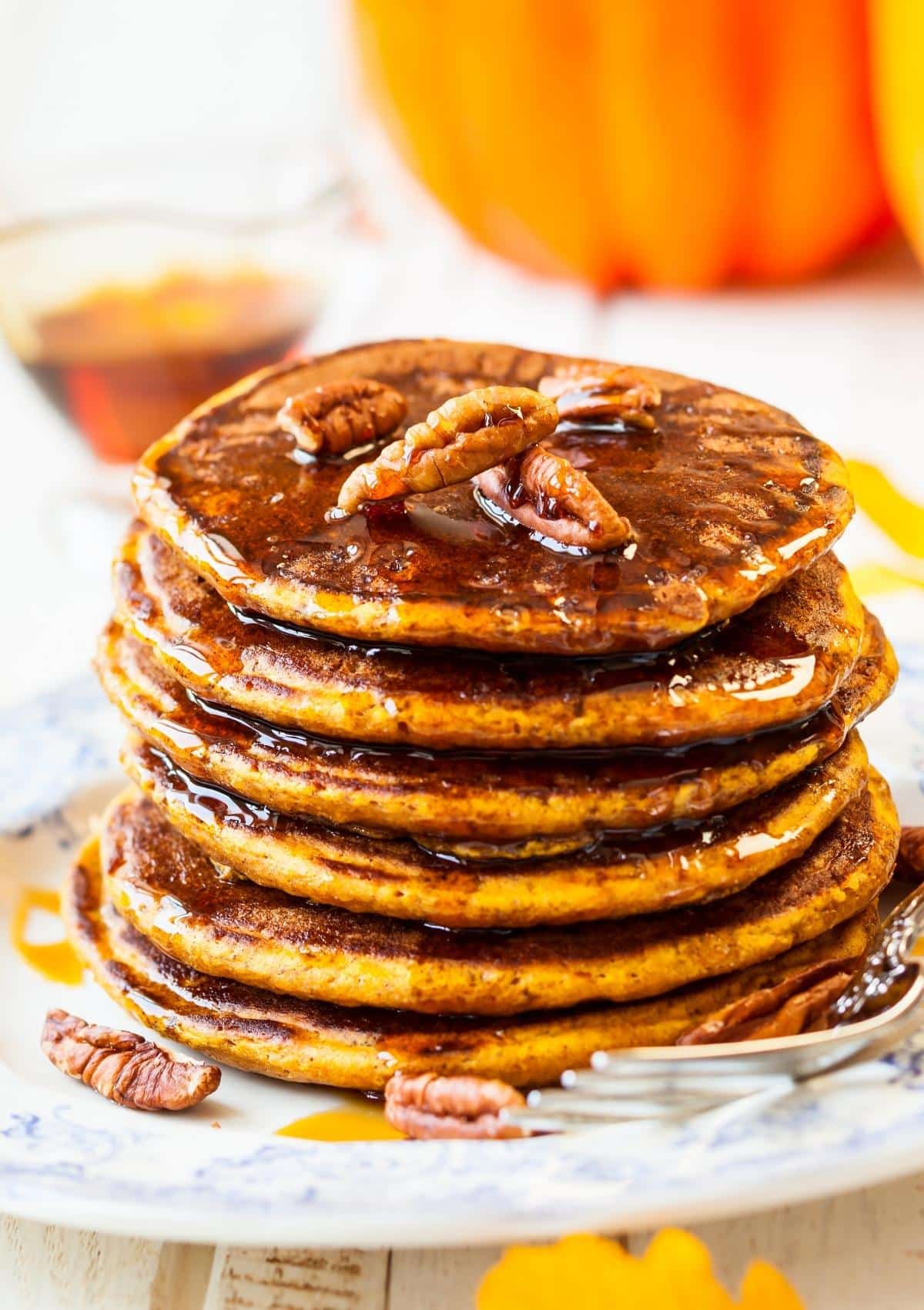 A stack of vegan pumpkin pancakes topped with maple syrup