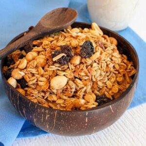 Wooden bowl filled with vegan granola and wooden spoon.
