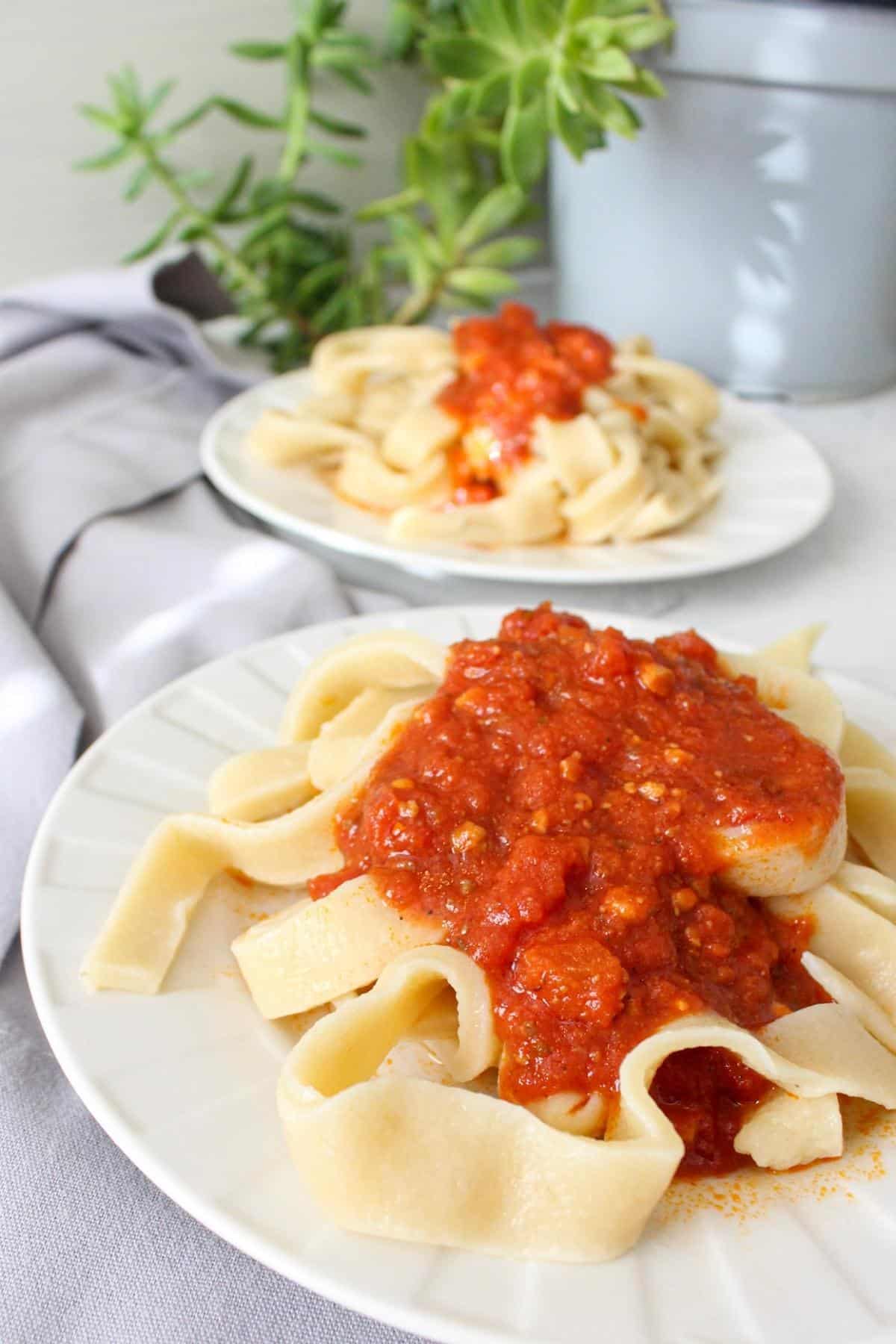 homemade vegan pasta noodles on plates with red sauce