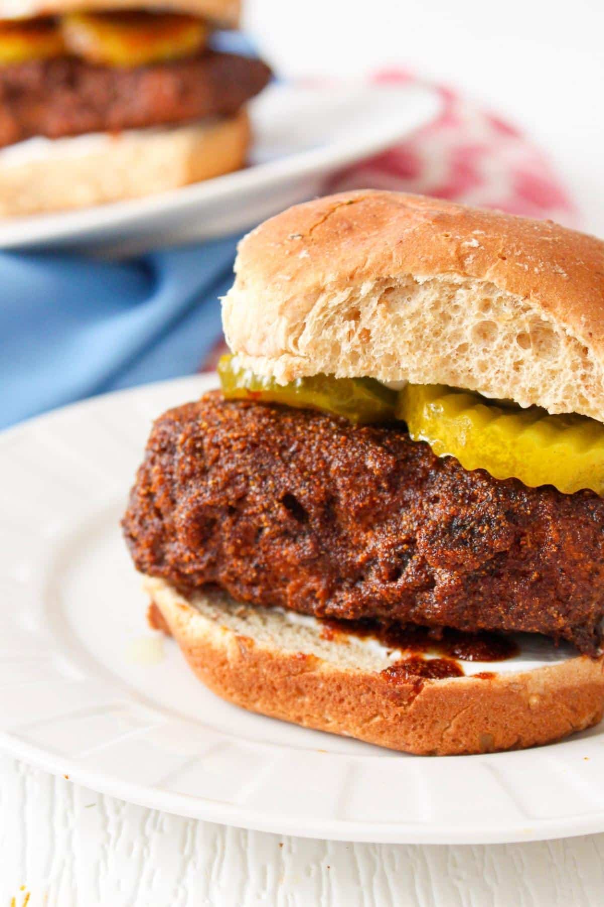 close up of nashville hot tempeh sandwich on a bun with pickles