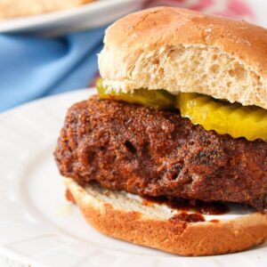 Close up of tempeh nashville hot sandwich on a burger bun with pickles