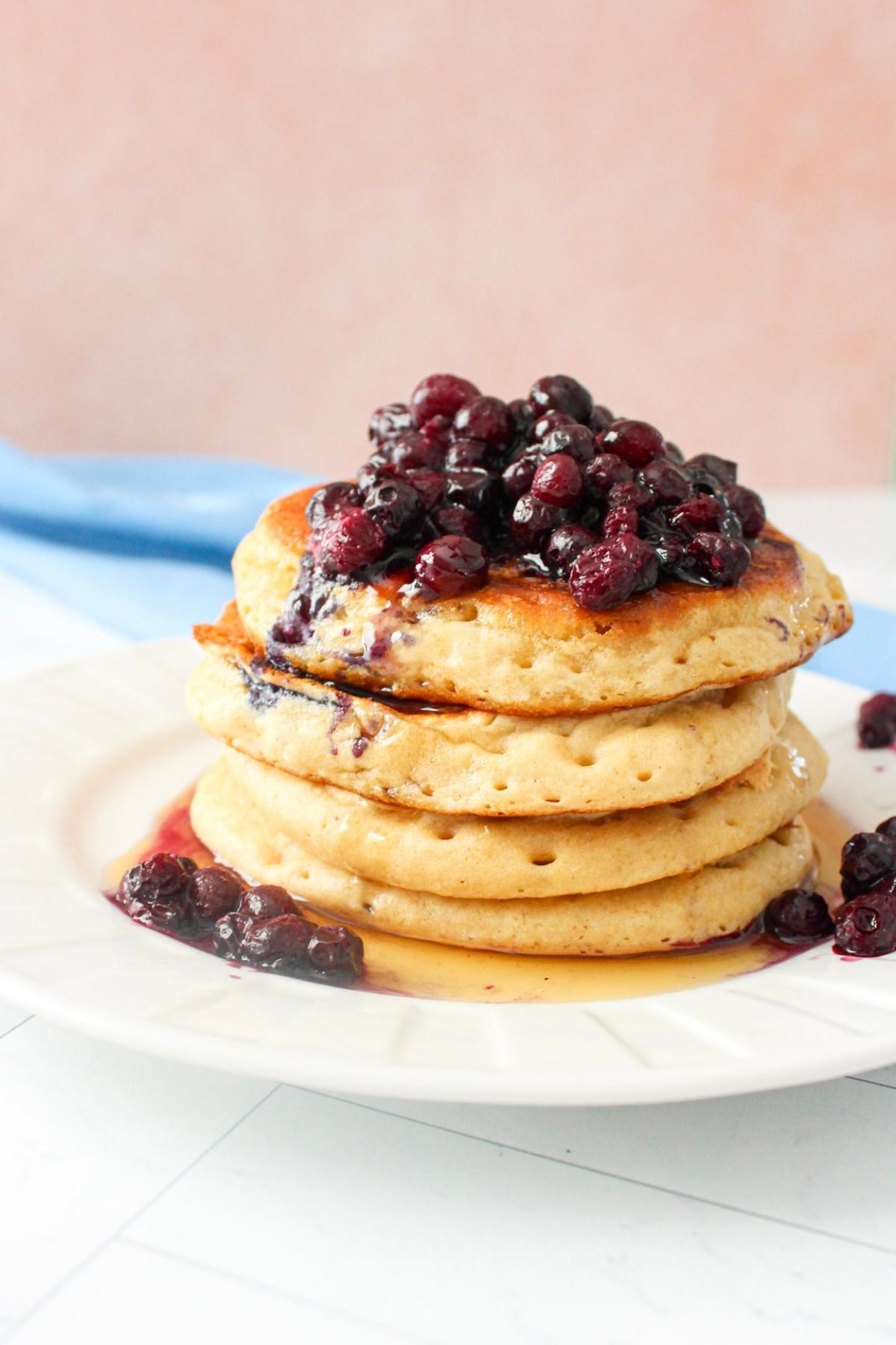 Stack of protein vegan pancakes on a plate topped with blueberries