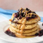 Stack of protein vegan pancakes on a plate topped with blueberries