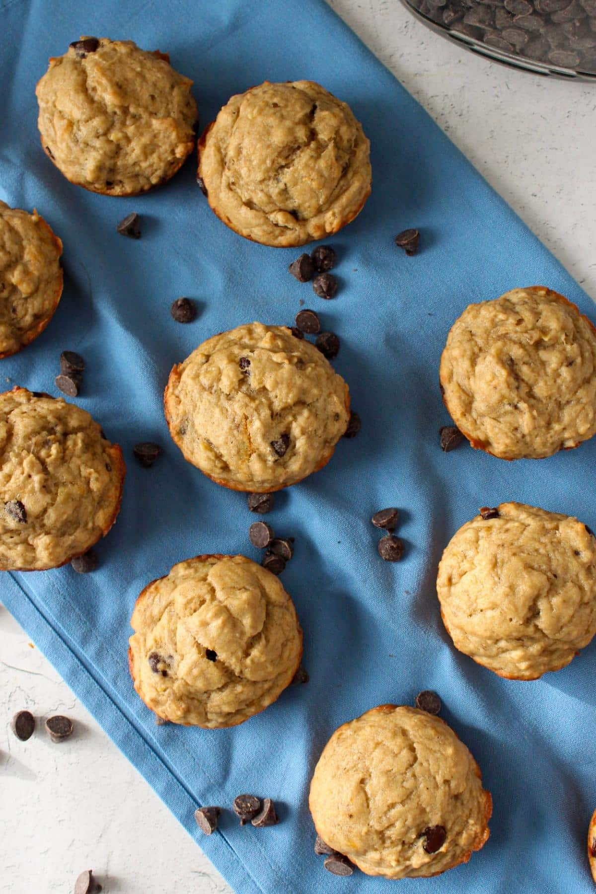 Overhead view of vegan banana chocolate chip muffins on a blue napkin