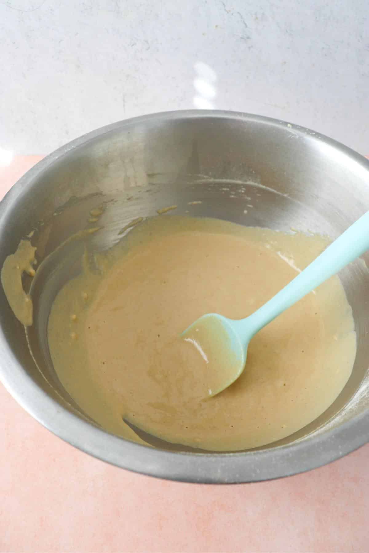 Vegan protein pancakes batter in a mixing bowl with a rubber spatula.