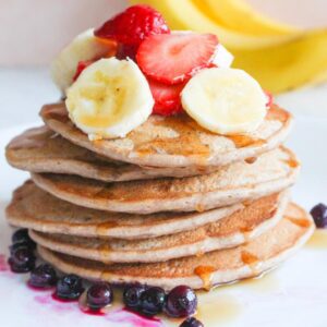 Close up of banana protein pancakes with bananas and strawberries on top.