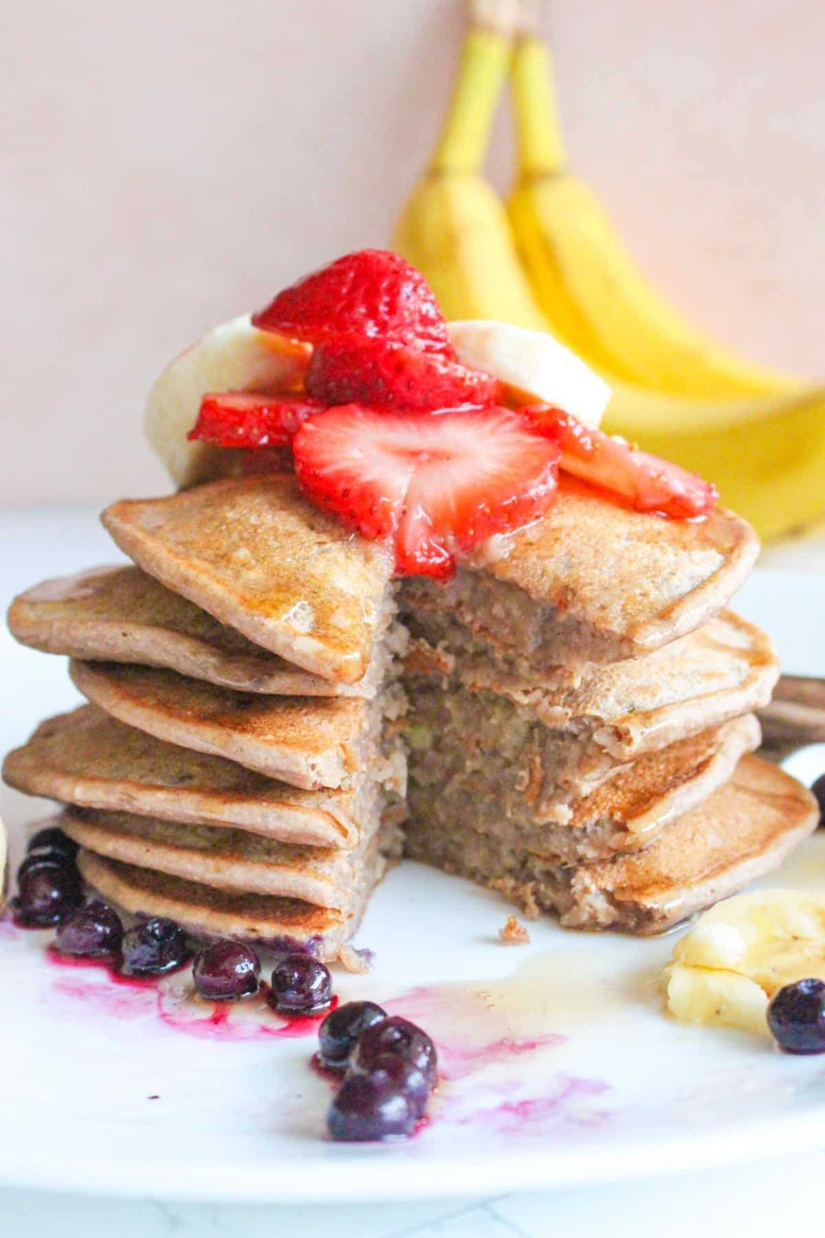 Banana protein pancakes stacked on each other, with a piece cut out of the middle.