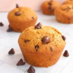 Vegan chocolate chip muffins on a counter with chocolate chips