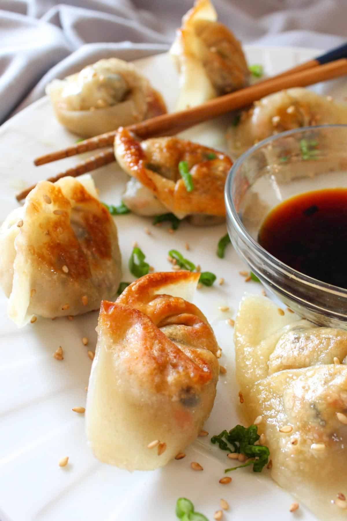 Plate full of vegan dumplings with soy sauce.