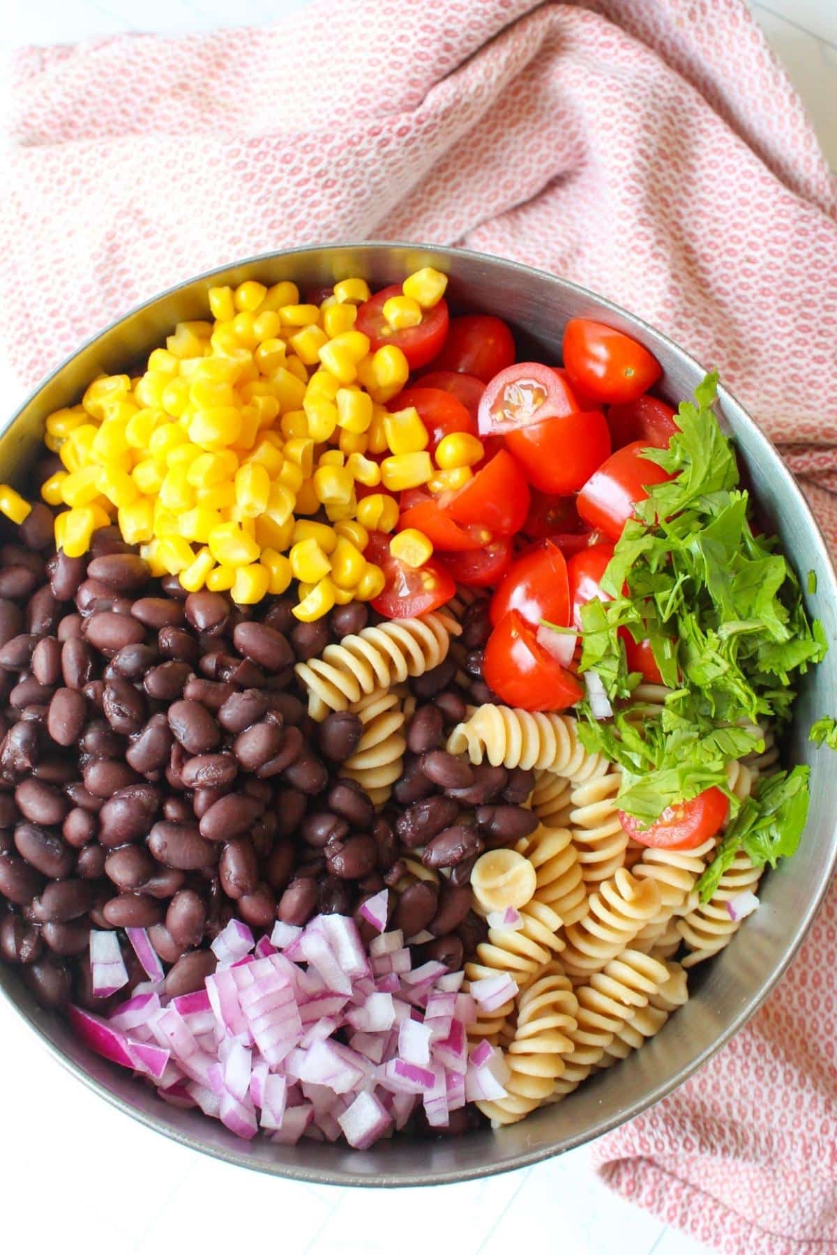 Ingredients for taco pasta salad in a mixing bowl, but not mixed together yet.