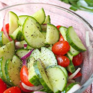 Close up of southern cucumber tomato salad in a glass serving bowl.