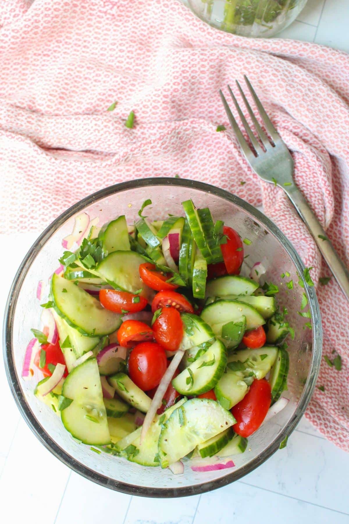 Overhead shot of cucumber tomato salad in a glass bowl.