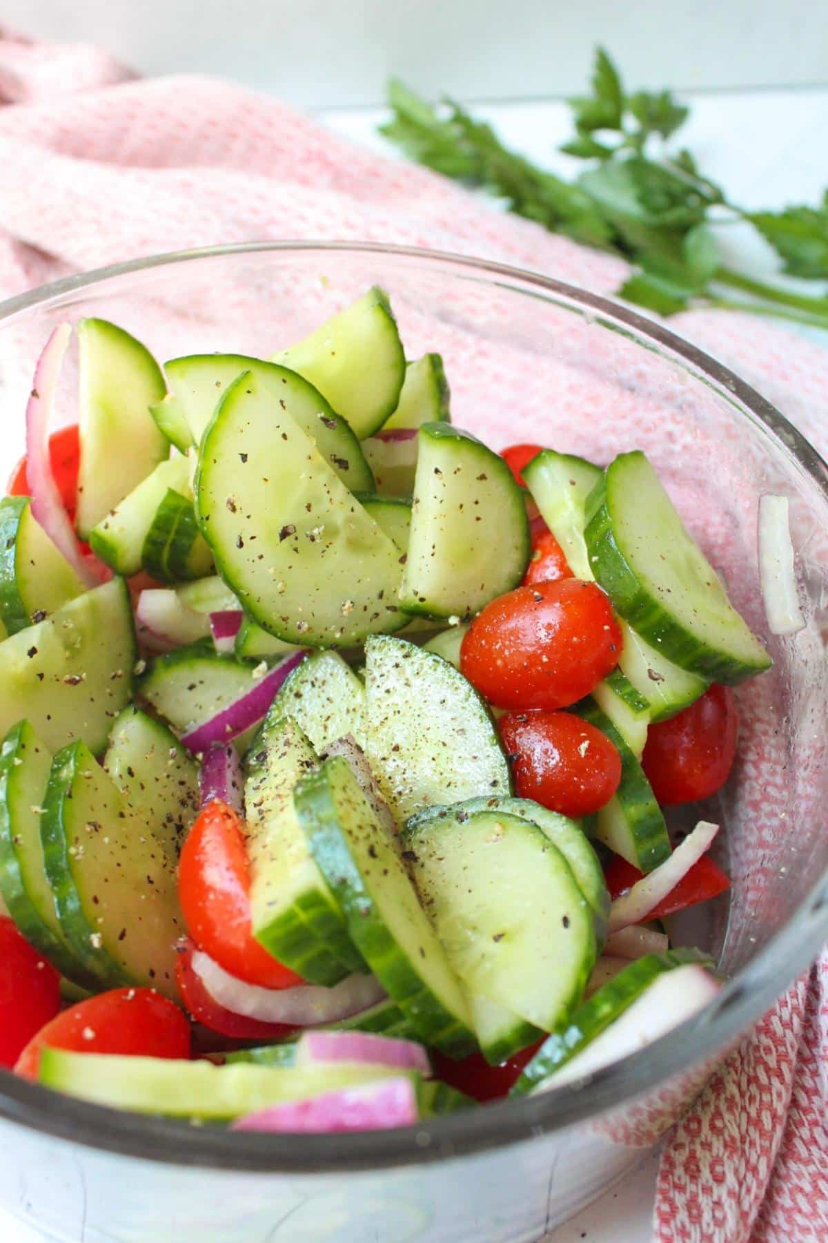 Glass serving bowl of southern cucumber tomato salad.