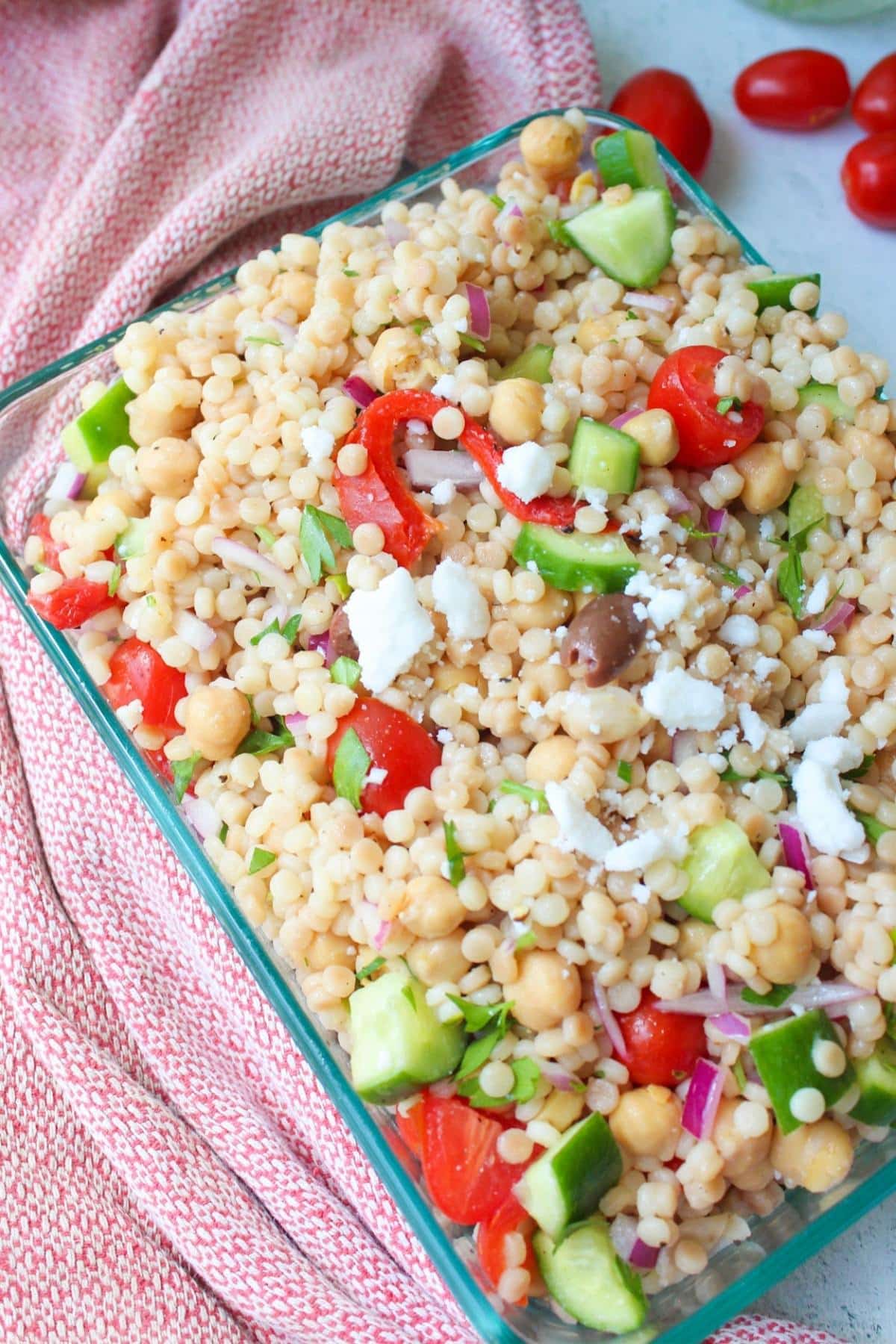Israeli couscous vegetable salad in a glass serving dish.