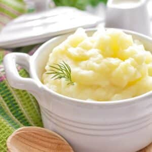 Creamy vegan instant pot no drain mashed potatoes in a serving dish on a table.