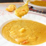 Instant pot red lentil soup in a bowl with a spoon dipped in.