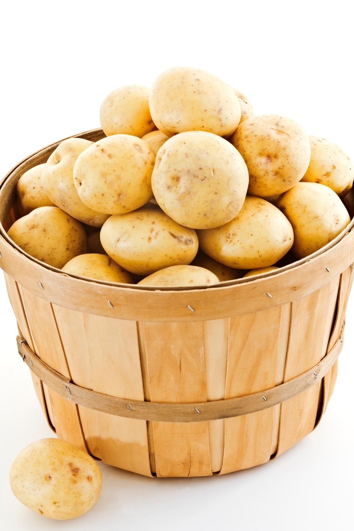 A wooden basket full of Yukon gold potatoes