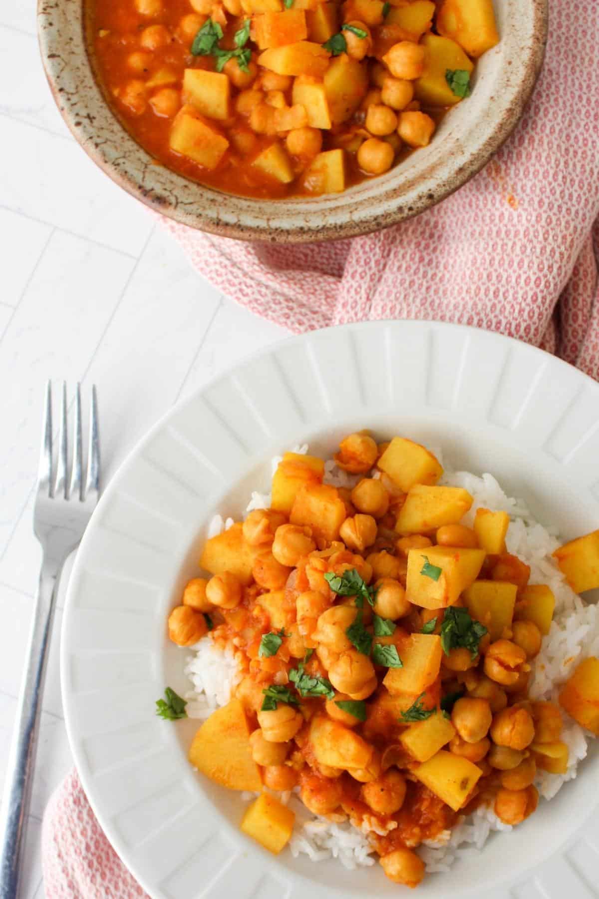 Overhead shot of chickpea and potato curry in a bowl over rice.