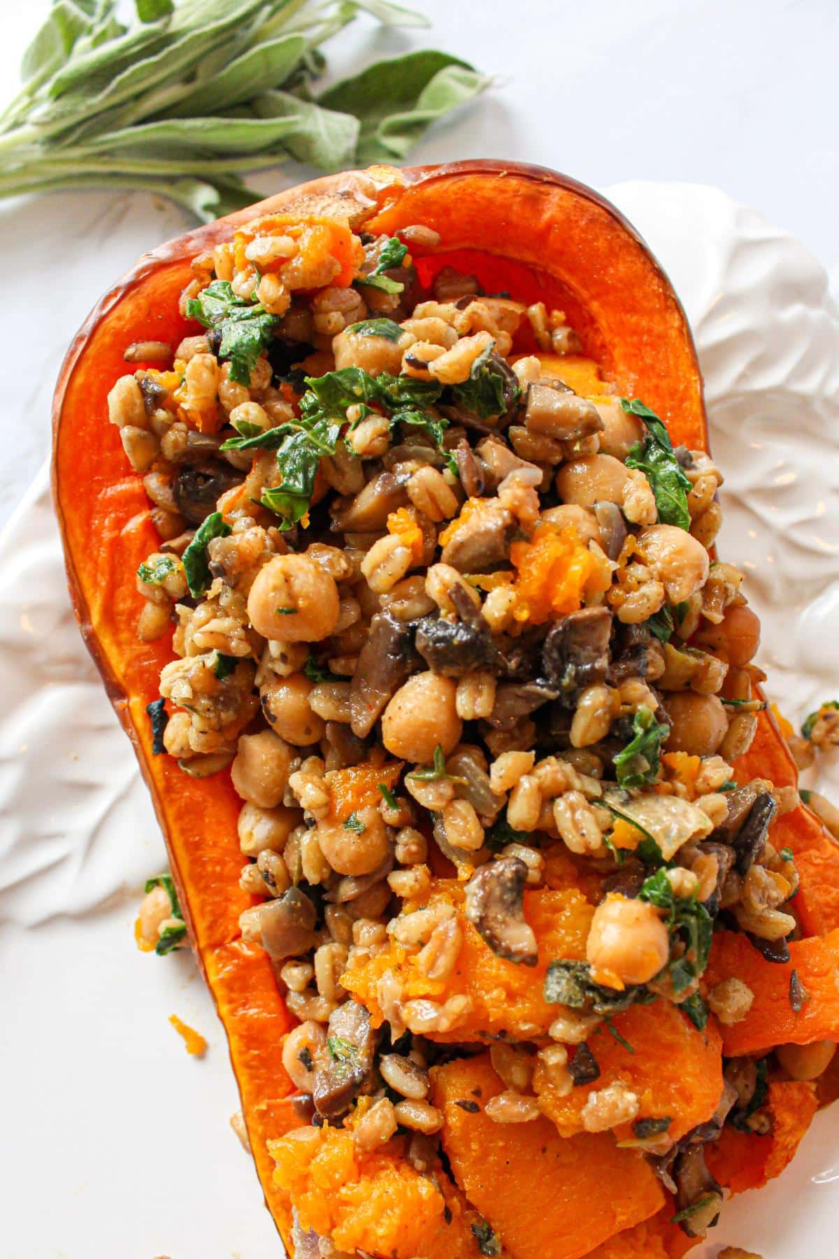 Vegan stuffed butternut squash on a serving dish with grains, mushrooms and chickpeas