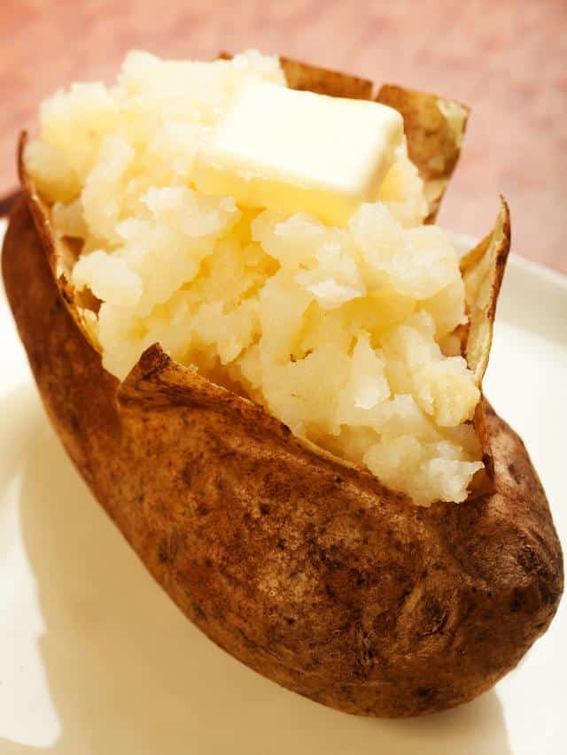 Baked potato baked in the air fryer on a plate with butter.