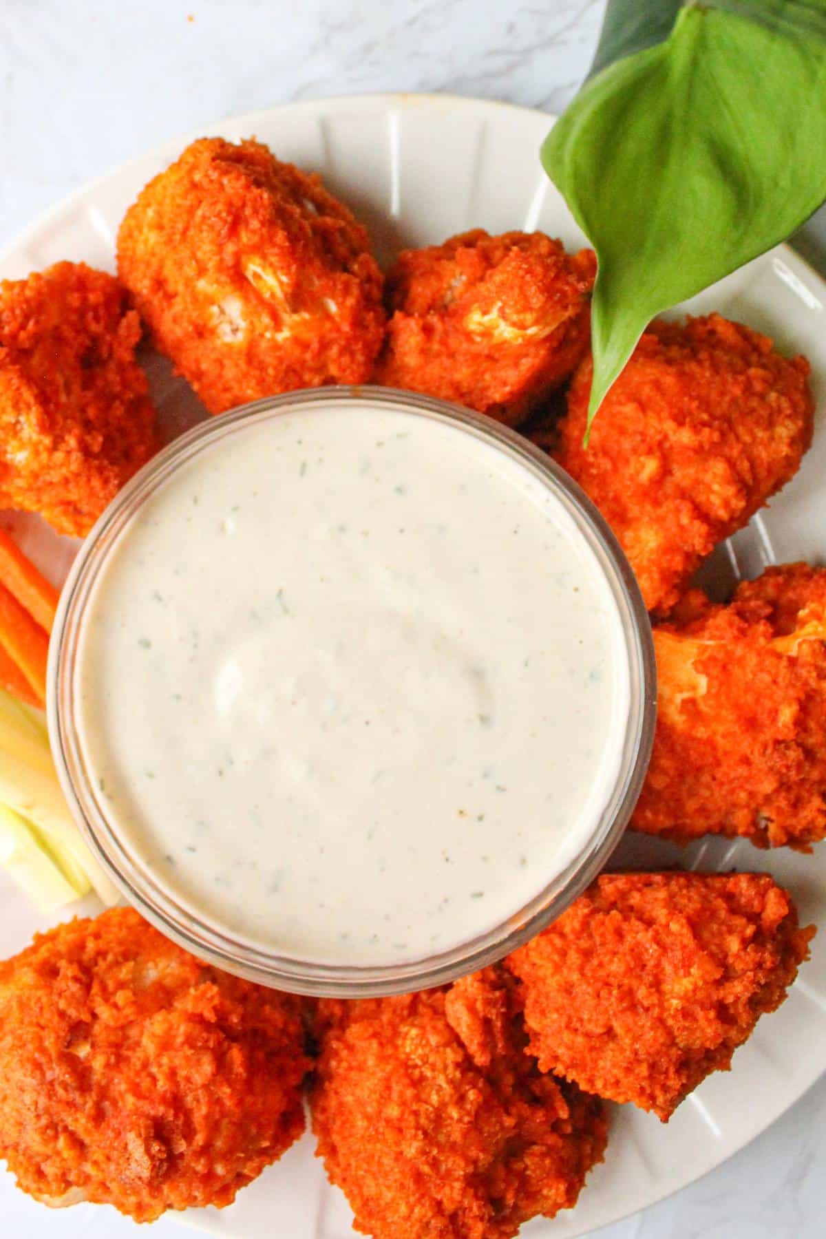 Vegan wings surrounded by a small bowl of vegan ranch dressing.