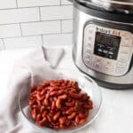 Kidney beans cooked in an instant pot in a bowl next to an instant pot.