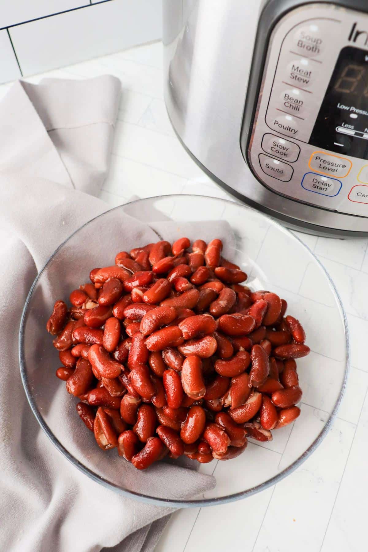Bowl of kidney beans that were cooked in an instant pot next to an instant pot.