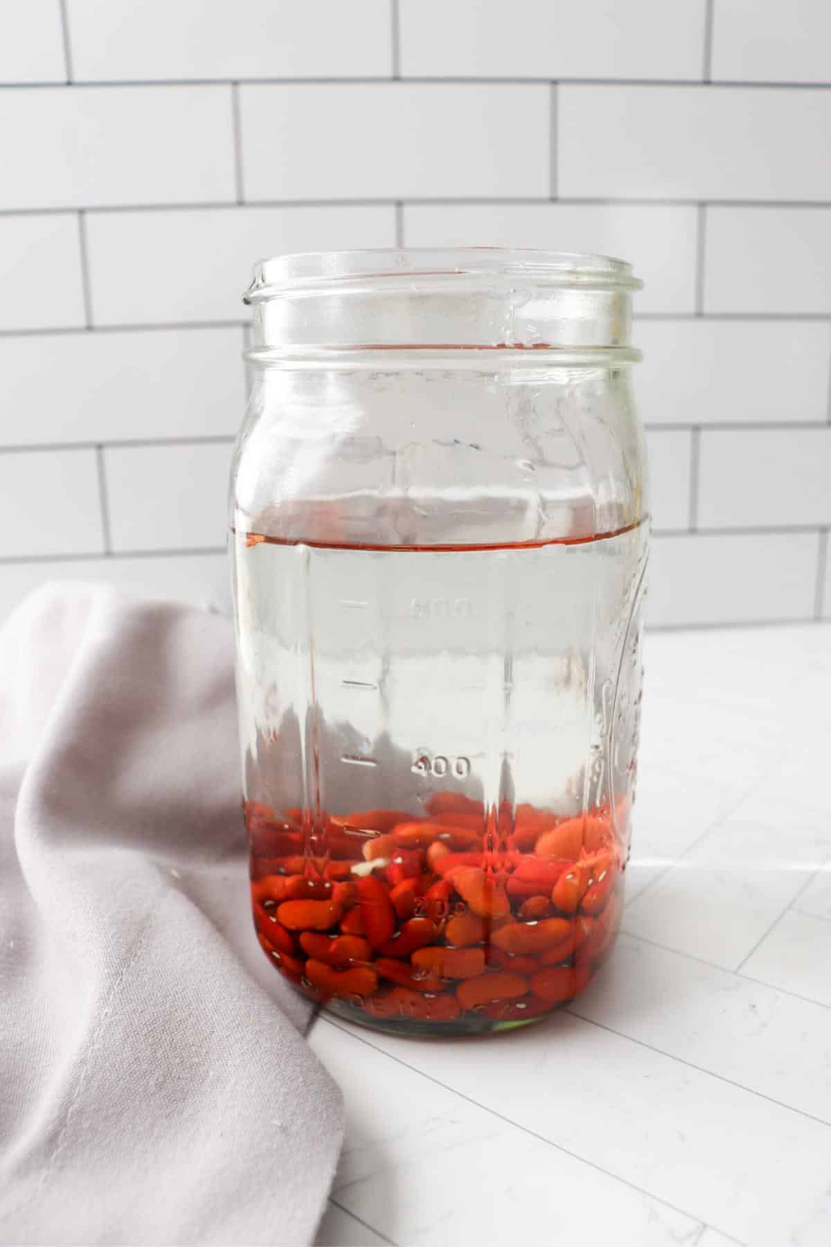 Dry kidney beans soaking in a mason jar of water.