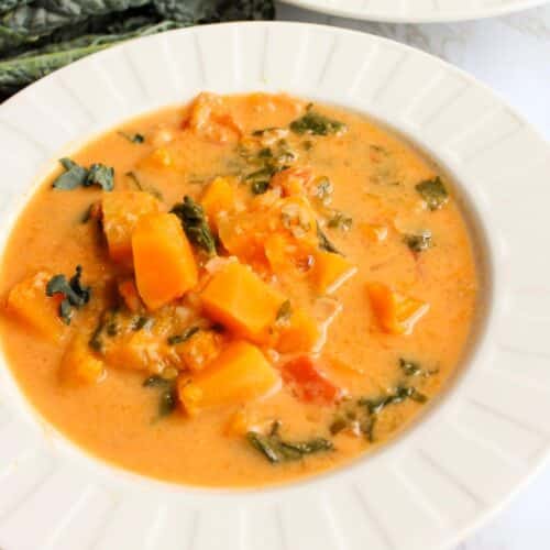 Chunky butternut squash soup with kale in a white bowl.