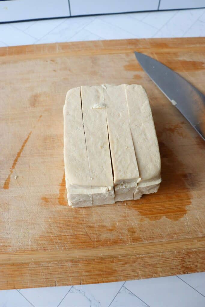 Tofu block being cut into strips.