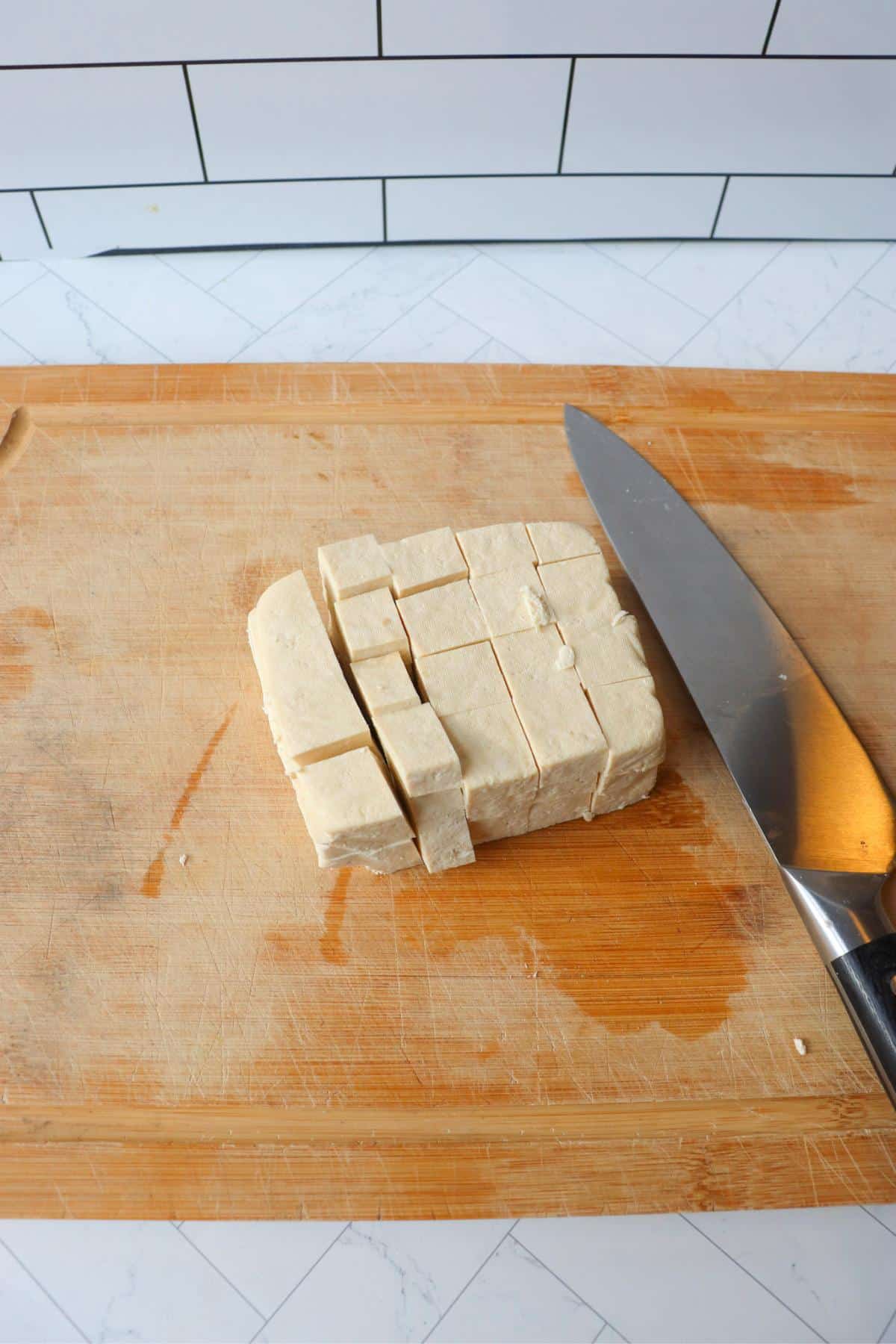 Tofu block being cut into cubes.