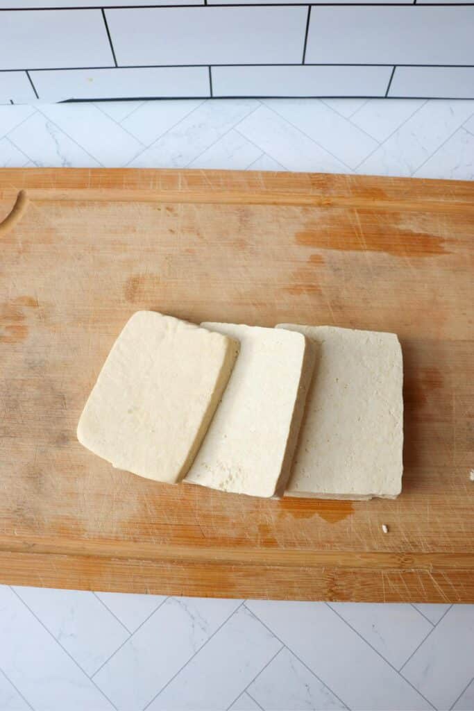 Tofu block being cut into three slices.
