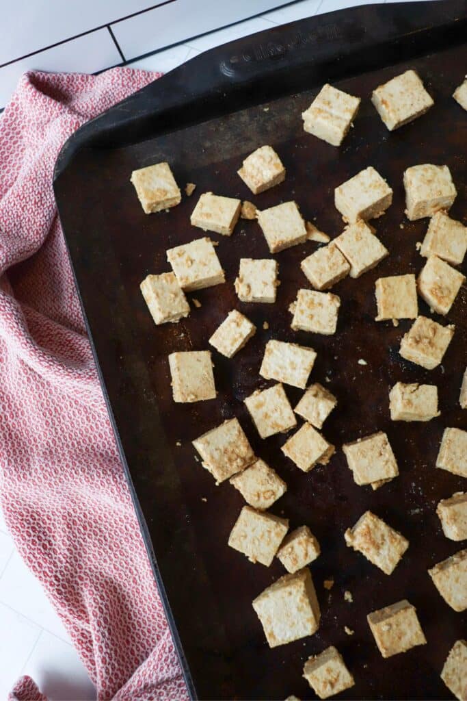 Tofu cubes on a baking sheet before going in the oven.